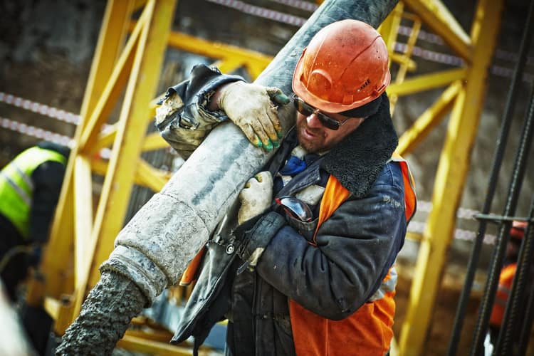 A worker guiding a concrete pump hose during a pour