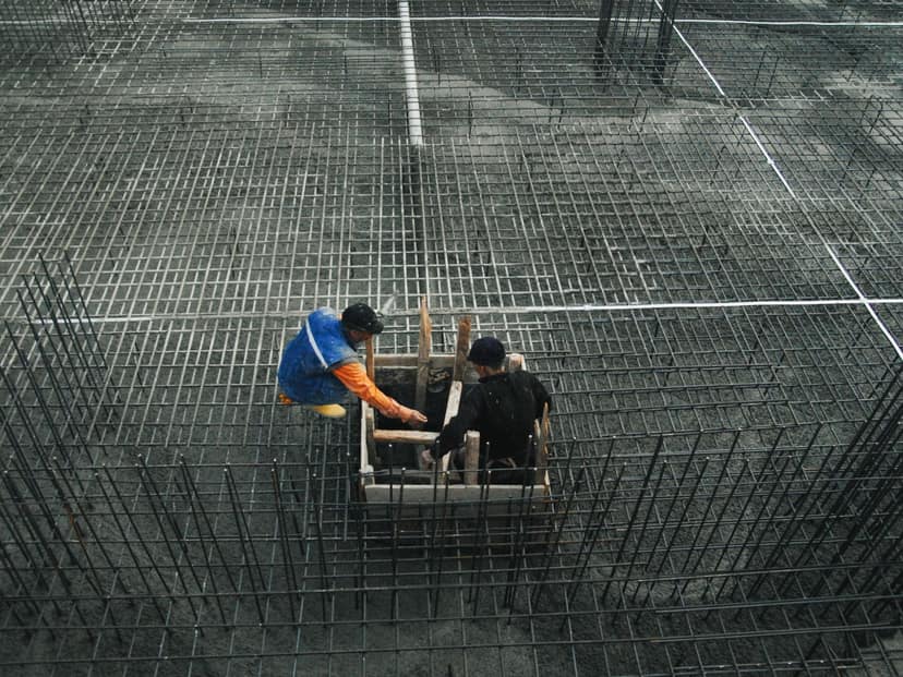 Two workers setting formwork on a reinforcing steel mat