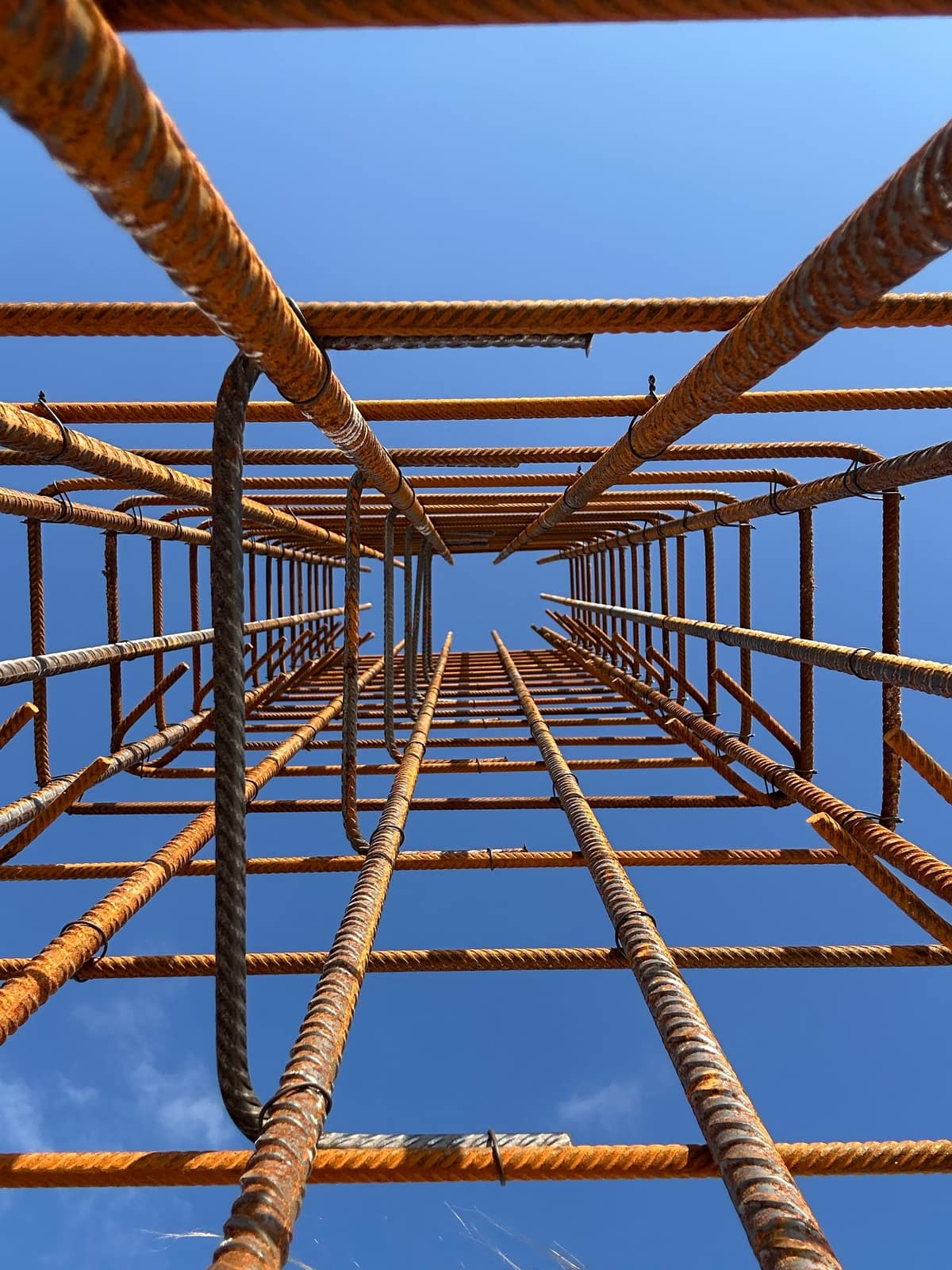 Looking up through a reinforcing steel cage against open sky